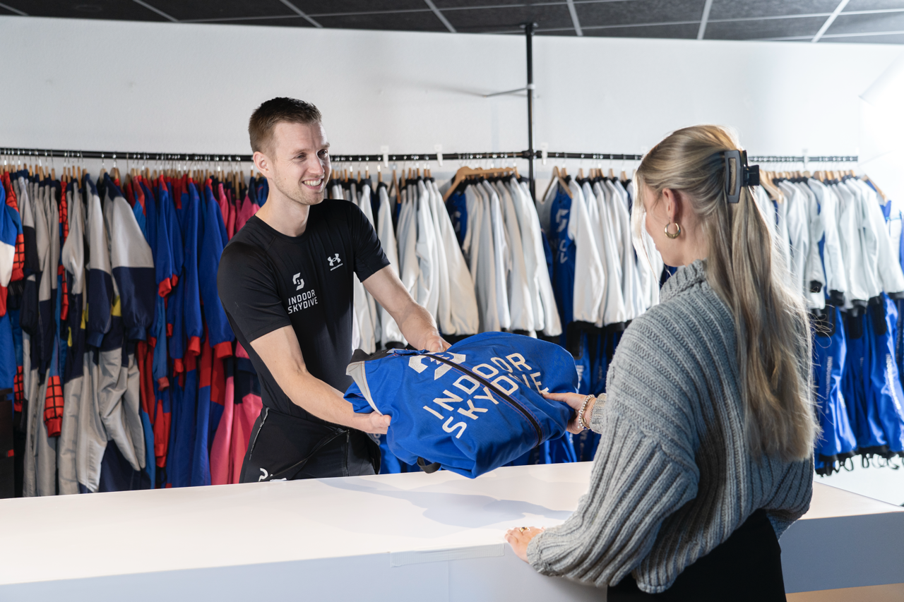 Medewerker overhandigt skydivekleding